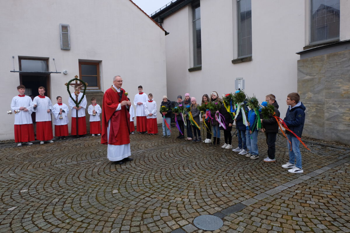 Pfarrer Schemmerer segnet auf dem  Kirchplatz die Palmzweige