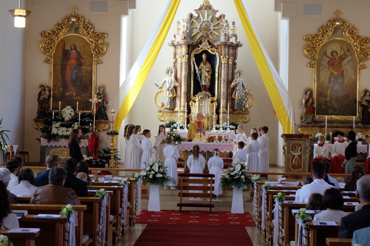 Die Erstkommunionkinder stehen zur Erneuerung des Taufgelübtes mit ihren Kommunionkerzen um den Altar